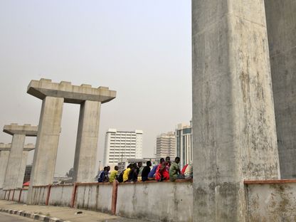 أشخاص يجلسون على الحافة بين أعمدة خط سكة حديد قيد الإنشاء في لاغوس ، نيجيريا - المصدر: بلومبرغ