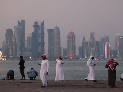 مواطنون ومقيمون يتنزهون عند كورنيش الدوحة فيما تبدو في الأفق ناطحات السحاب في العاصمة القطرية - المصدر: بلومبرغ