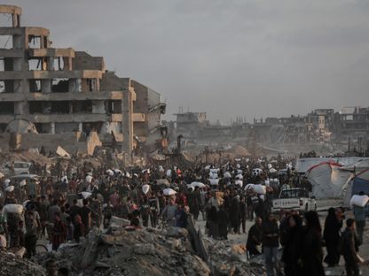 فلسطينيون يحملون أكياساً من الدقيق من نقطة توزيع المساعدات في شمال غزة. 17 يونيو 2025 - بلومبرغ