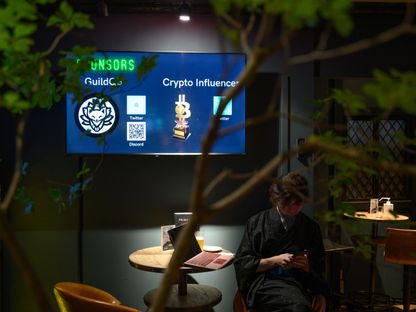 شاشة تعرض شعار \"غيلد كيو بي\" (GuildQB) و\"كريبتو إنفلونسر\" (Crypto Influencer) في \"كريبتو بار بي تو بي\" (CryptoBar P2P) بمنطقة غينزا في طوكيو، اليابان. - المصدر: بلومبرغ