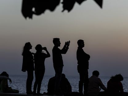 عدد من الأشخاص يلتقطون صوراً في \"مارين درايف\" عند غروب الشمس. مومباي، الهند - المصدر: بلومبرغ