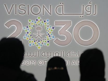 سيدات يقفن أمام شعار رؤية 2030 خلل مؤتمر بالعاصمة السعودية الرياض (أرشيفية) - المصدر: بلومبرغ