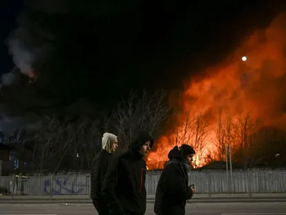 شبان يمرون بجانب مخزن يحترق بعد قصف على العاصمة الأوكرانية (صورة أرشيفية) - المصدر: بلومبرغ