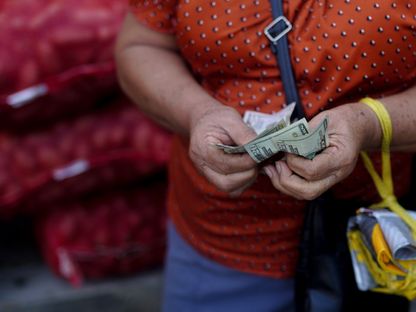 شخص في أحد الأسواق يدفع ثمن البضائع باستخدام أوراق نقدية من الدولار الأميركي - بلومبرغ