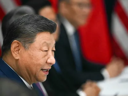 الرئيس الصيني شي جين بينغ، ويظهر يجواره مسؤولون صينيون، وفي الخلفية علم الصين وعلم الولايات المتحدة - AFP