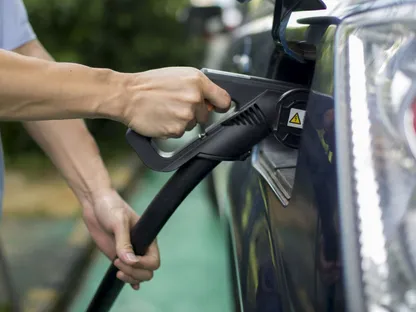 شخص يوصل سيارة كهربائية بالشاحن - المصدر: بلومبرغ