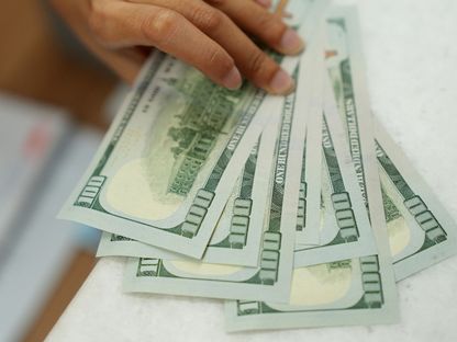 رجل يمسك بأوراق نقدية من فئة مئة دولار أميركي - المصدر: بلومبرغ