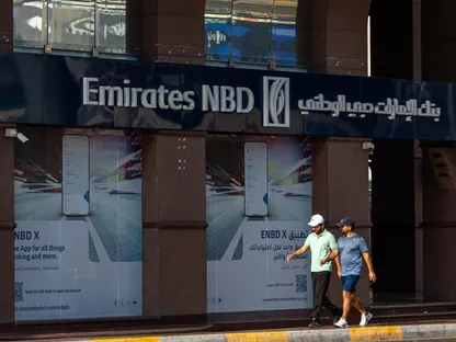 شخصان يمران أمام فرع لبنك الإمارات دبي الوطني بأبوظبي، الإمارات. - بلومبرغ