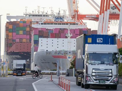 سفينة الحاويات \"وان هاي 331\"، التي تُشغّلها شركة \"وان هاي لاين\" (Wan Hai Line Ltd)، إلى اليمين، وسفينة الحاويات \"بوسورخا إكسبريس\"، التي تُشغّلها شركة \"هاباغ-لويد\" (Hapag-Lloyd AG)، ترسو في محطة شحن في يوكوهاما، اليابان. - بلومبرغ