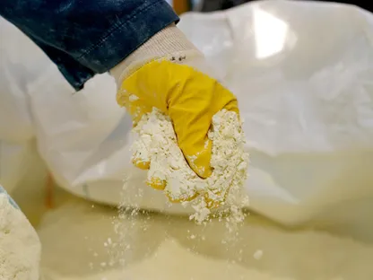 شخص يرتدي قفازاً يمسك بحفنة أكاسيد عناصر أرضية نادرة - بلومبرغ