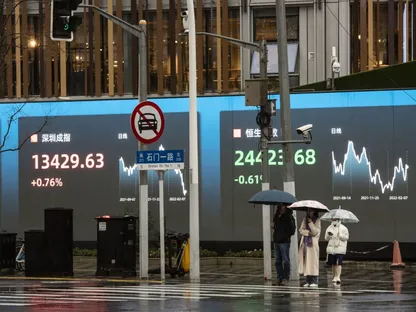 مشاة ينتظرون لعبور طريق أمام شاشة عامة تعرض أرقام مؤشرَي \"شنزن\" و\"هانغ سنغ\" في شنغهاي، الصين. - المصدر: بلومبرغ