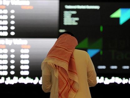 رجل بالزي التقليدي السعودي يتابع حركة الأسهم على لوحة إلكترونية في سوق الأسهم السعودية. الرياض. المملكة العربية السعودية - المصدر: بلومبرغ