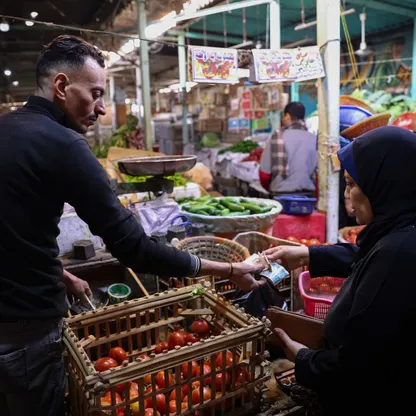 سيدة تدفع ثمن مشترياتها من الخضار في سوق للأغذية في الأزهر، القاهرة، مصر - بلومبرغ