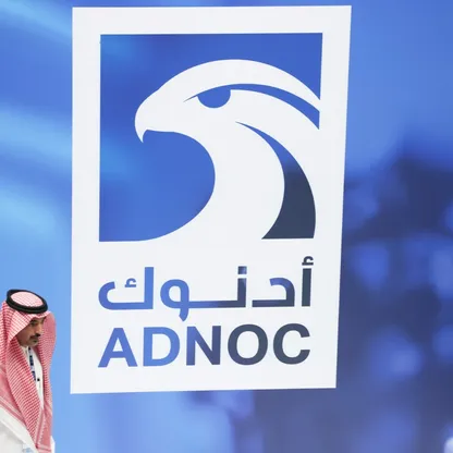 شخص يمر أمام جدار مثبت عليه شعار "أدنوك". تراهن "أدنوك للتوزيع" على السوق المصرية من خلال التوسع في محطات وقود باستثمارات قيمتها مليار دولار. - بلومبرغ