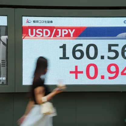 امرأة تمر أمام شاشة تعرض سعر صرف الين مقابل الدولار الأميركي خارج إحدى شركات الأوراق المالية في طوكيو، اليابان - بلومبرغ
