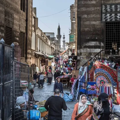 مجموعة من المارة وباعة جوالين بشارع به مبانٍ أثرية قديمة في مصر - المصدر: بلومبرغ