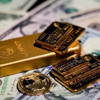 سبائك ذهبية وعملة ذهبية موضوعة فوق أوراق نقدية من فئة الدولار الأميركي لدى شركة تجارة سبائك الذهب "غولدن مارك" في وارسو، بولندا - بلومبرغ