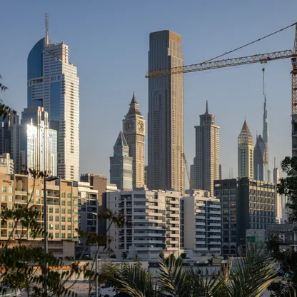 ونش إنشاءات بالقرب من مبانٍ سكنية في دبي، الإمارات. وسط فتور العقارات، دبي تضخ 1.4 مليار دولار في مركزها المالي. - بلومبرغ