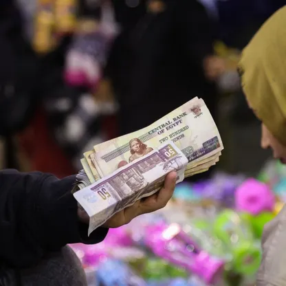 بائع مصري يمسك بيديه رزمة من الأوراق النقدية بالجنيه المصري - المصدر: بلومبرغ