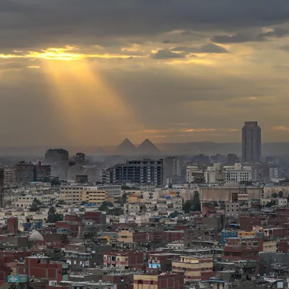 صورة تظهر مباني سكنية وتجارية في مدينة القاهرة، وفي الخلفية أهرامات الجيزة، مصر. - المصدر: بلومبرغ