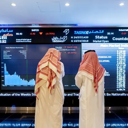 شخصان يتفقدان أسعار الأسهم المعروضة على شاشة رقمية داخل سوق الأسهم السعودية في الرياض، المملكة العربية السعودية (صورة أرشيفية) - بلومبرغ