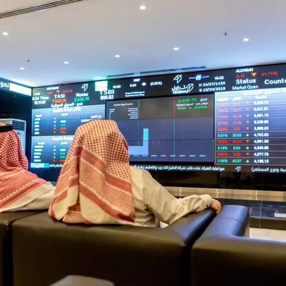 شخصان يتابعان معلومات أسعار الأسهم المعروضة على شاشة رقمية داخل السوق المالية السعودية (تداول) - صورة أرشيفية - المصدر: بلومبرغ