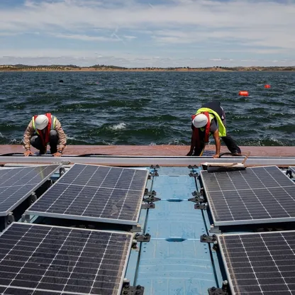 فنيان يعدان محطة طاقة شمسية عائمة تستخدم في خزان في ألكيفا في البرتغال. - المصدر: بلومبرغ