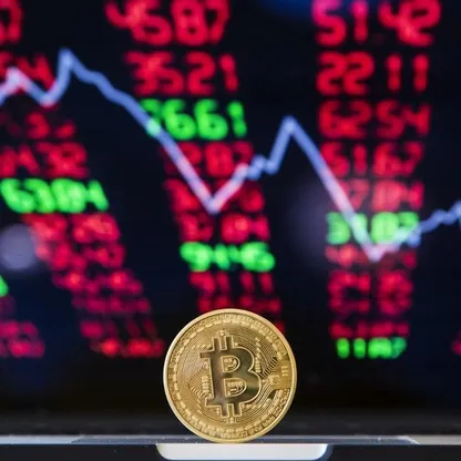 قطعة رمزية تحمل شعار العملة المشفرة "بتكوين" وفي الخلفية صورة رسم بياني لحركة الأسعار في السوق - AFP
