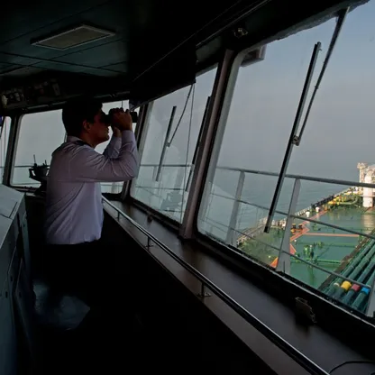 أحد أفراد الطاقم يستخدم منظاراً على جسر ناقلة النفط 'ديفون' أثناء استعدادها لنقل النفط الخام من محطة النفط في جزيرة خرج الإيرانية إلى الهند. - المصدر: بلومبرغ