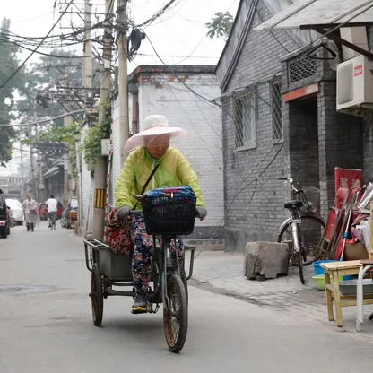امرأة عجوز تقود دراجتها في زقاق هوتونغ في بكين، الصين - المصدر: بلومبرغ