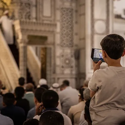 طفل يصور بهاتفه الذكي خطبة أحد رجال الدين في الجامع الأموي بوسط دمشق قبل صلاة الجمعة خلال عيد الأضحى المبارك. يوم 6 يونيو 2025 - بلومبرغ