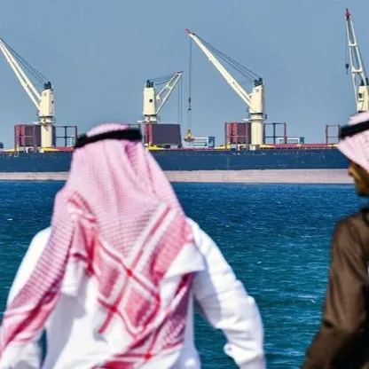 مواطنان سعوديان ينظران إلى ناقلة نفط راسية في ميناء رأس الخير على الساحل الشرقي للمملكة العربية السعودية - المصدر: بلومبرغ