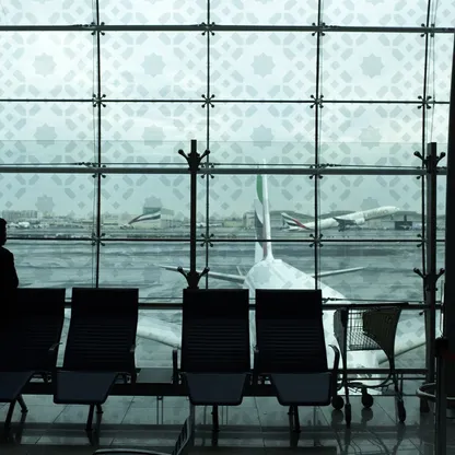 أحد المسافرين في قاعة الانتظار ينظر باتجاه ناقلة جوية تابعة لشركة طيران الإمارات في مطار دبي. الإمارات العربية المتحدة - المصدر: بلومبرغ