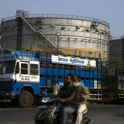 شاحنات لنقل أسطوانات الغاز أمام خزانات للنفط في الهند - بلومبرغ