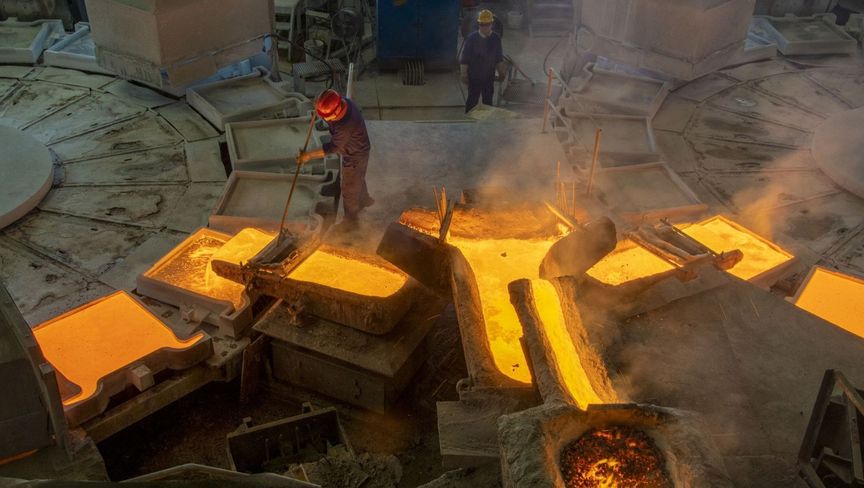 عمال يملئون هياكل معدنية بالحديد المنصهر في منشأة صناعية  - المصدر: غيتي إيمجز