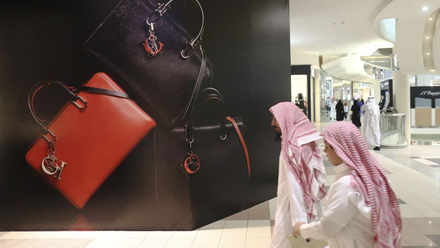 متسوقان بالزي الوطني السعودي يمران أمام إعلان للحقائب الفاخرة في أحد المراكز التجارية في الرياض - بلومبرغ