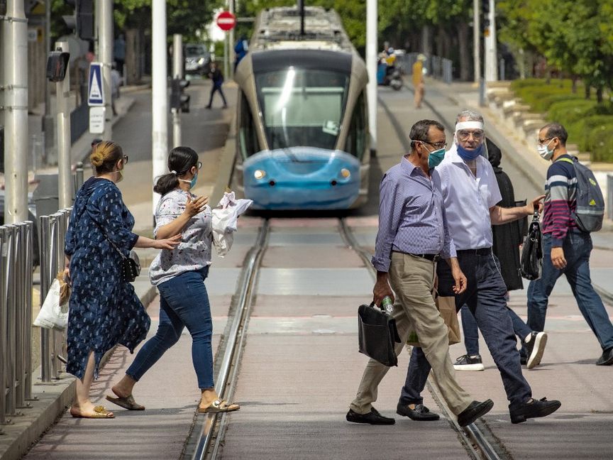 مارة يعبرون طريقاً فيما يقترب ترام من بلوغ محطة التوقف في وسط العاصمة المغربية الرباط - AFP