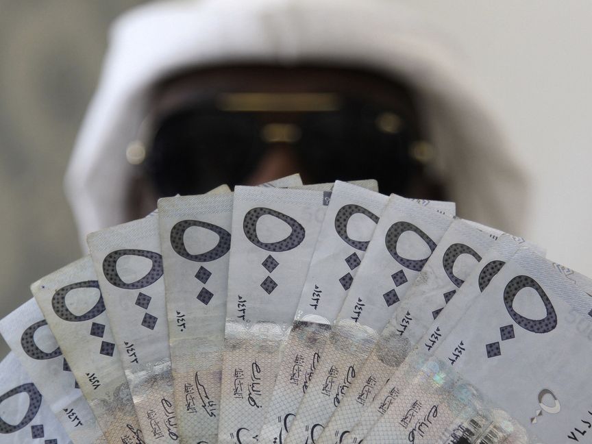 رجل يحمل أوراقاً نقدية من فئة 500 ريال سعودي في الرياض - المصدر: بلومبرغ