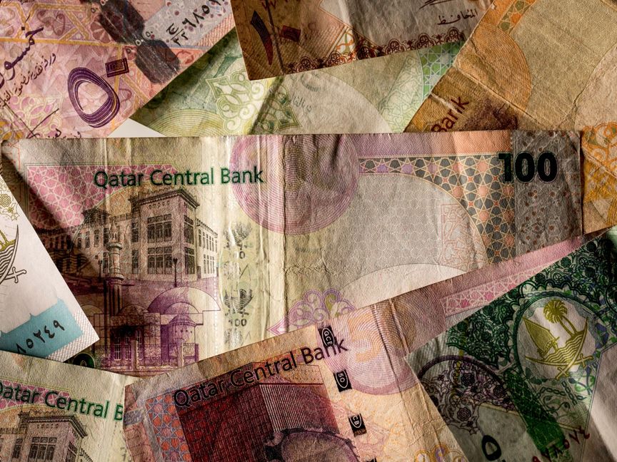 ورقة نقدية من فئة 100 ريال وسط عملات من فئات أخرى من إصدار بنك قطر المركزي - المصدر: بلومبرغ