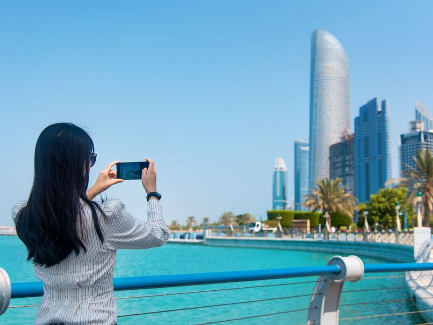 سائحة تلتقط صورة للأبراج على كورنيش أبوظبي، الإمارات العربية المتحدة - المصدر: بلومبرغ