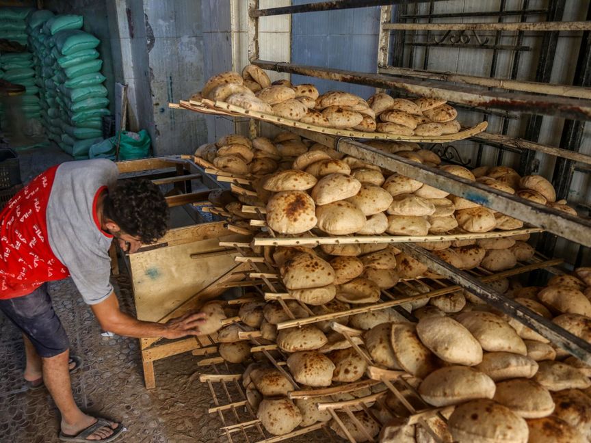 عامل يرتب الخبز البلدي الطازج داخل مخبز في منطقة الدقي بالجيزة، مصر - المصدر: بلومبرغ