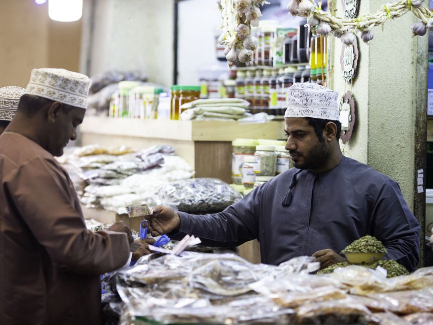 رجل يشتري بضائع من تاجر في سوق السيب في مسقط، سلطنة عمان - المصدر: بلومبرغ