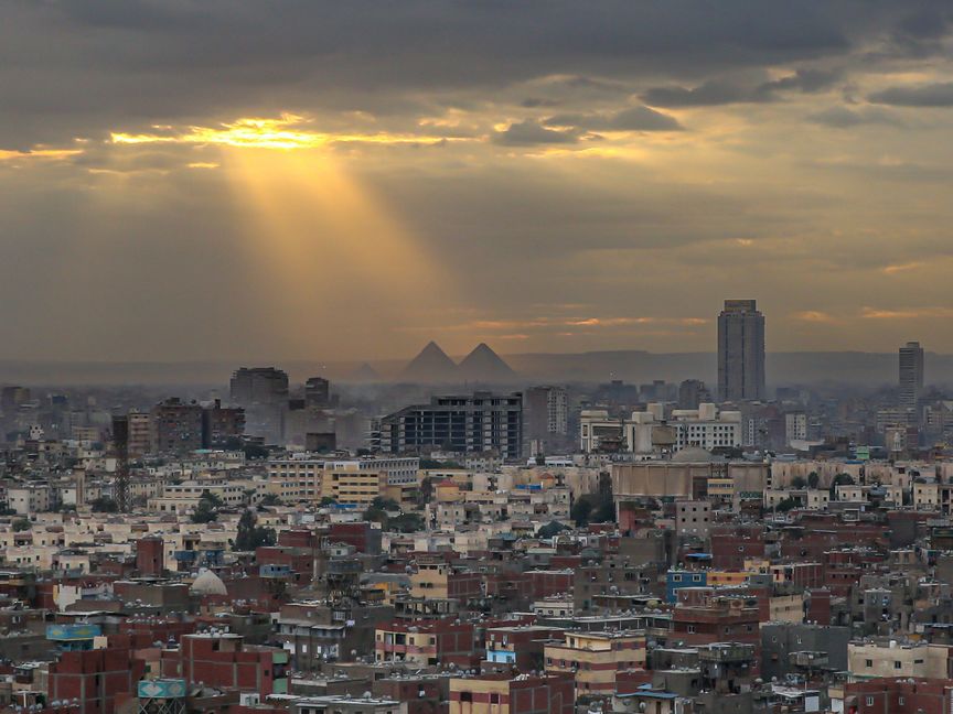 صورة تظهر مباني سكنية وتجارية في مدينة القاهرة، وفي الخلفية أهرامات الجيزة، مصر. - الشرق/بلومبرغ