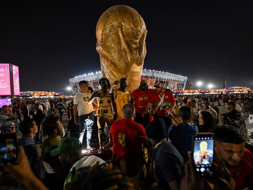 مشجعو فريقي غانا والبرتغال يتجمعون لالتقاط صور تذكارية أمام مجسم لكأس العالم في الدوحة. قطر - المصدر: بلومبرغ