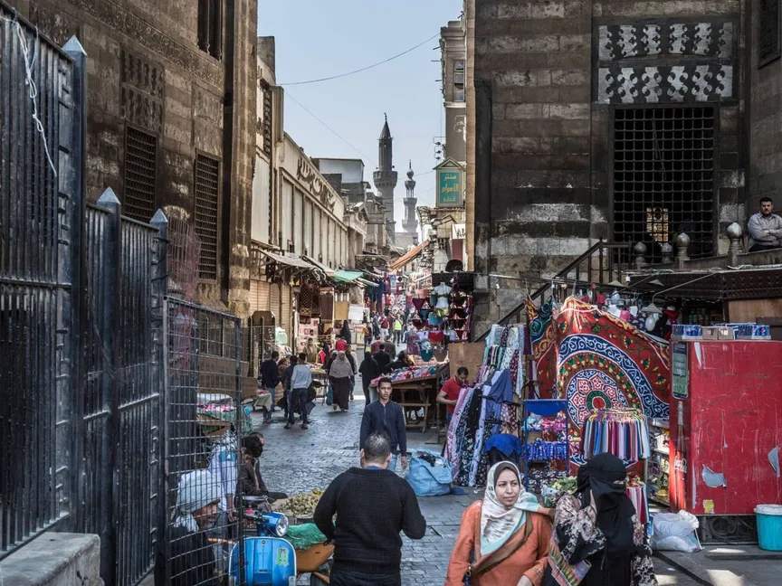 مجموعة من المارة وباعة جوالين بشارع به مبانٍ أثرية قديمة في مصر - المصدر: بلومبرغ