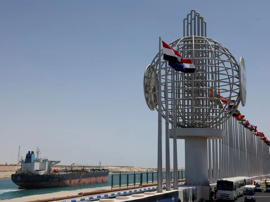 سفينة "شين يو" تبحر في قناة السويس، فيما ترفرف العديد من أعلام الدول على الضفة المقابلة، الإسماعلية، مصر، 16 أبريل 2025. - رويترز