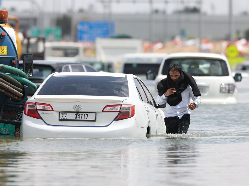 سائق يغادر سيارته ليشق طريقه وسط مياه غزيرة بسبب هطول شديد للأمطار في دبي، الإمارات، بتاريخ 17 أبريل 2024 - الشرق/بلومبرغ