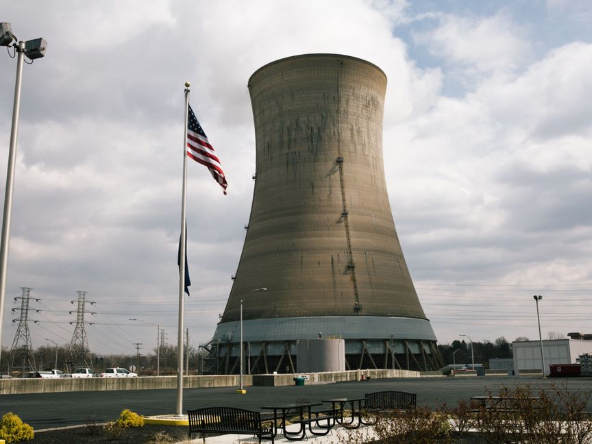 علم أمريكي يرفرف أمام برج تبريد في محطة الطاقة النووية Exelon Corp. Three Mile Island للطاقة النووية في ميدلتاون ، بنسلفانيا ، الولايات المتحدة - المصدر: بلومبرغ