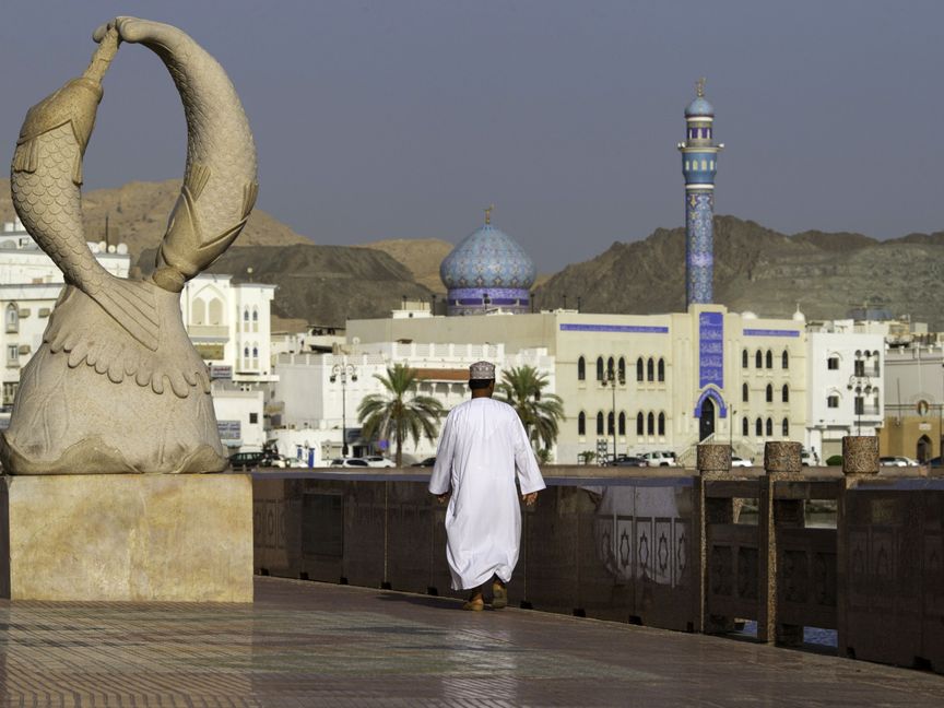 مواطن عُماني يسير على كورنيش مطرح الذي تصطف على جانبيه منازل تجار القرن التاسع عشر بمدينة مسقط القديمة ، عمان - المصدر: بلومبرغ