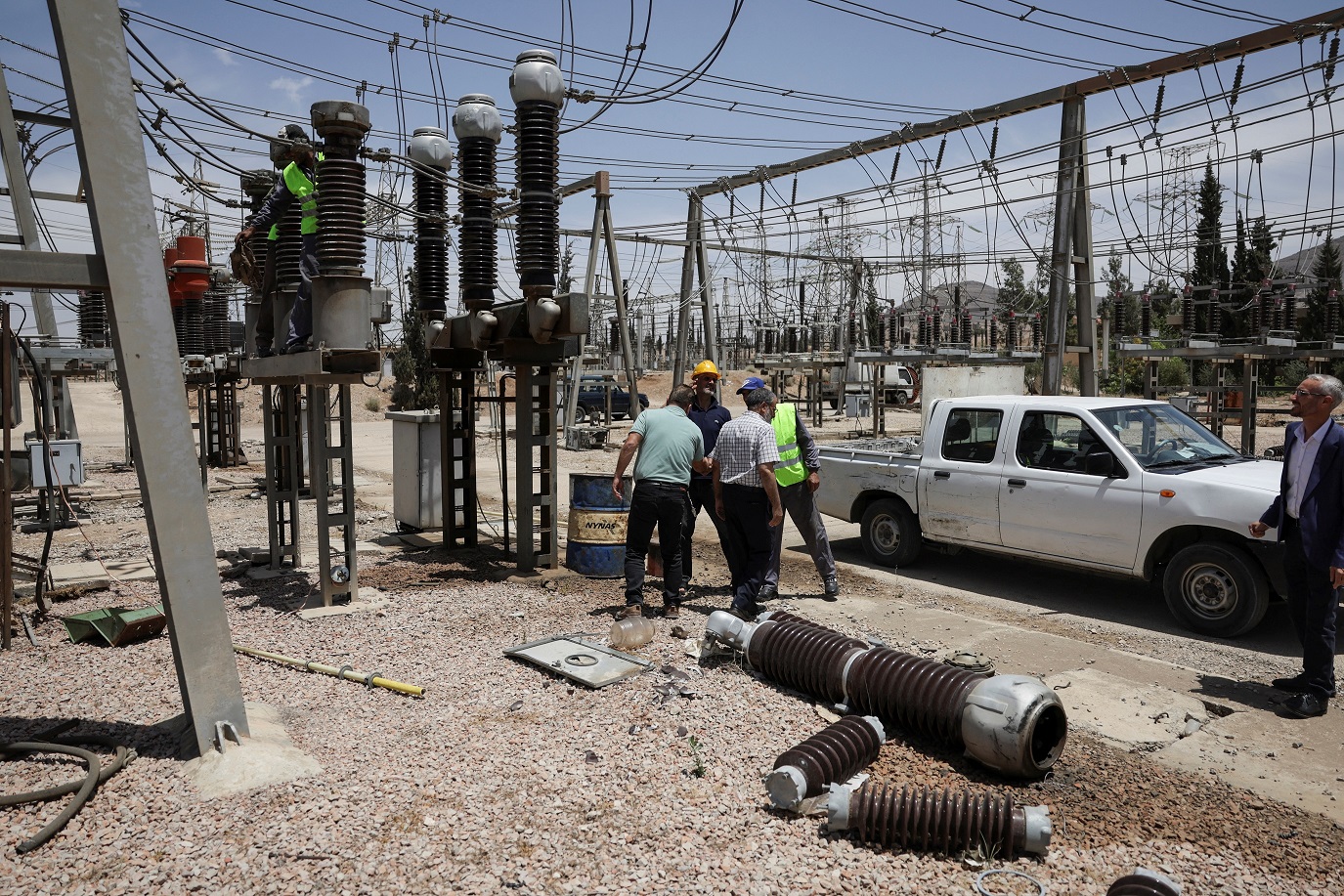 عمال يجرون أعمال صيانة لمحولات توليد الطاقة في منطقة الكسوة بريف دمشق، قرب العاصمة السورية دمشق، 26 مايو 2025 - رويترز